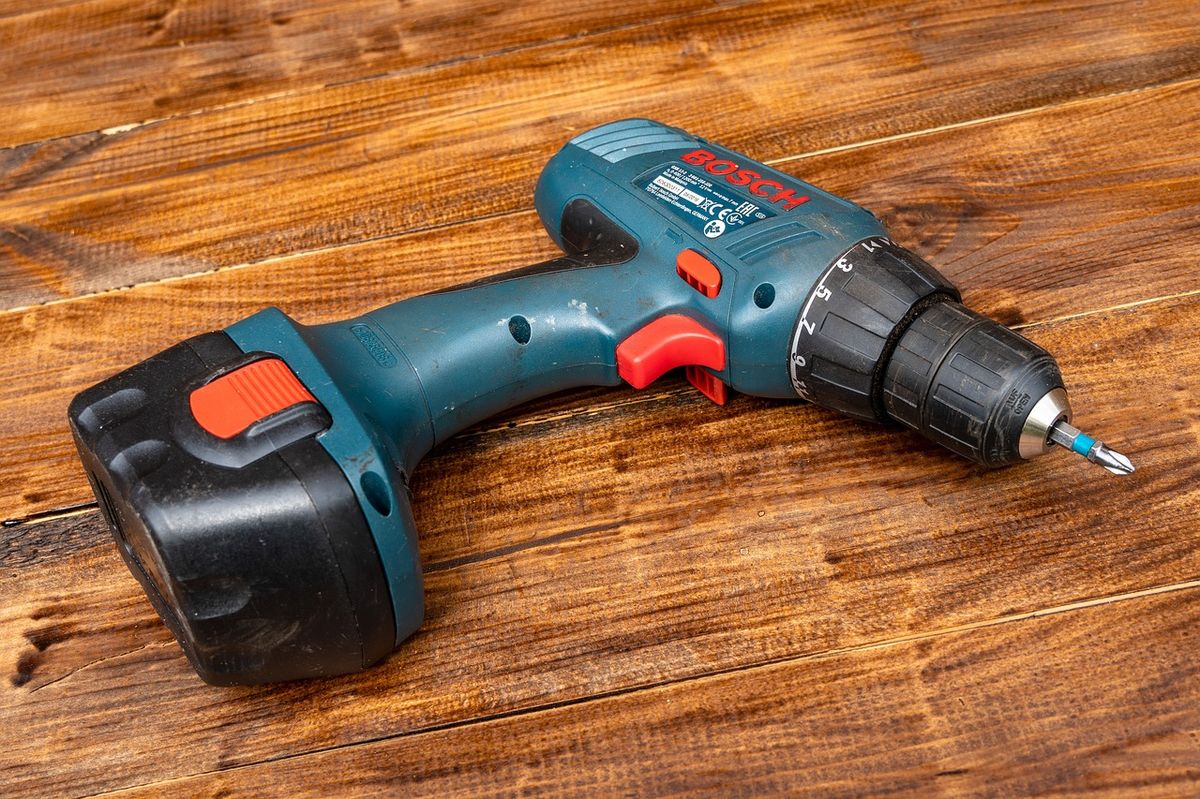 A cordless drill and screwdriver bits used for wall-mount installation