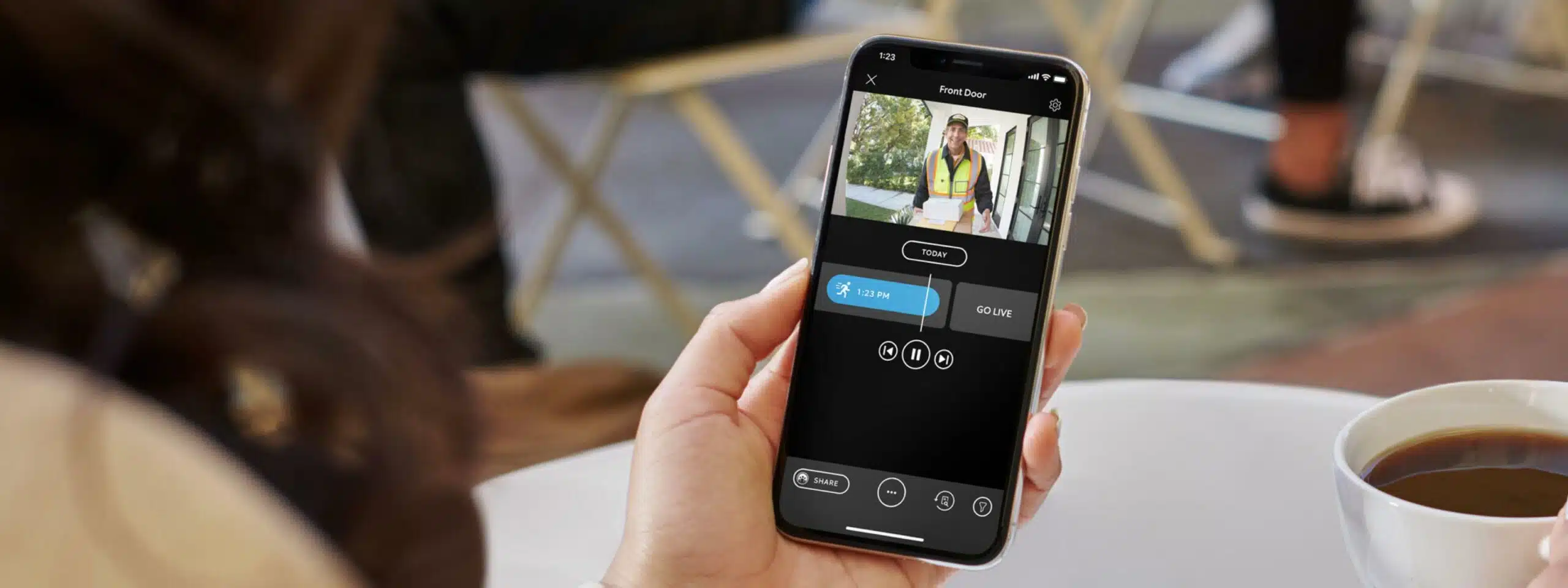 A woman is holding up a phone and a cup of coffee.