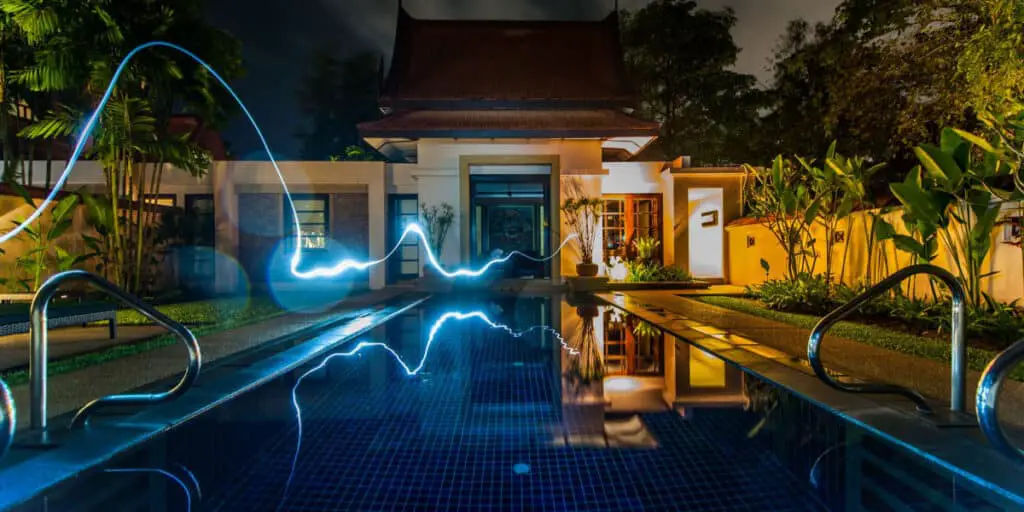 Smart Home Technology - The Pool In Front Of A House Is Illuminated With Light Streaks At Night.