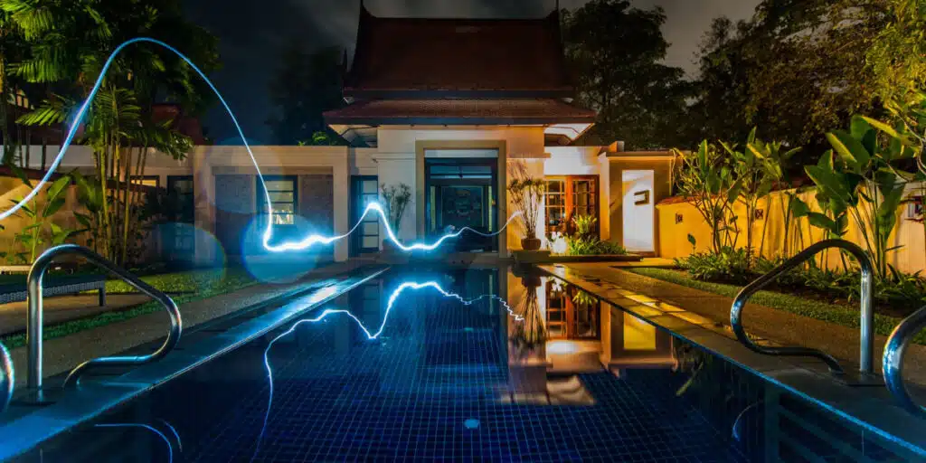 Smart Home technology - The pool in front of a house is illuminated with light streaks at night.