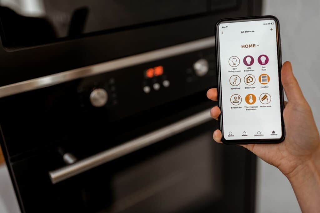 A Person Showcasing An Oven's Smart Capabilities Using A Smartphone.