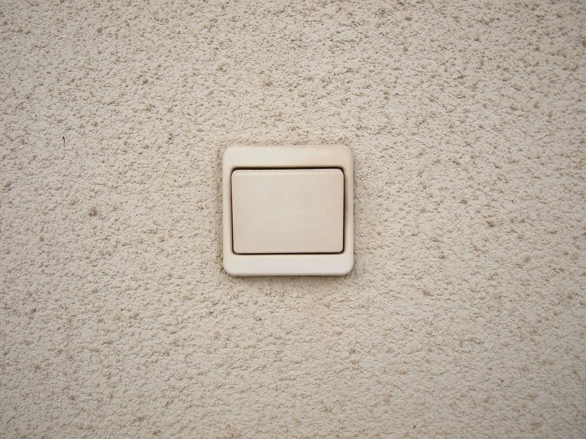 A simple wall-mounted light switch on a textured wall
